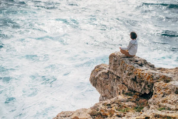 Vandrarkvinna sitter på kanten av en stenig strand. — Stockfoto