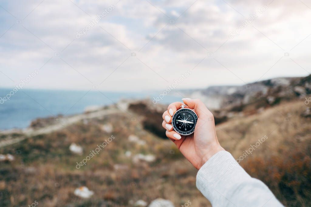 Woman hiker with a compass orientates herself in a mountainous area.