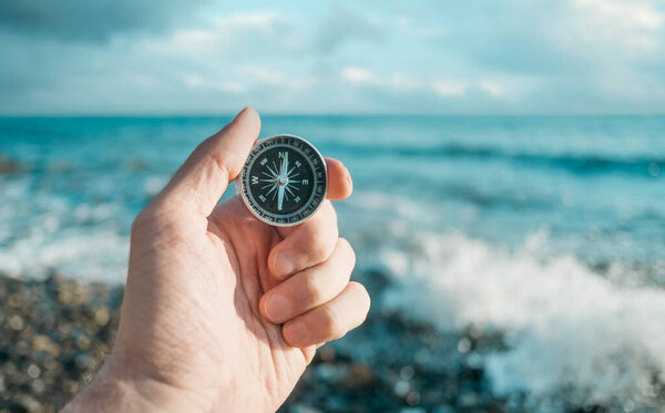 Compass in hand in the background the waves and the sea.
