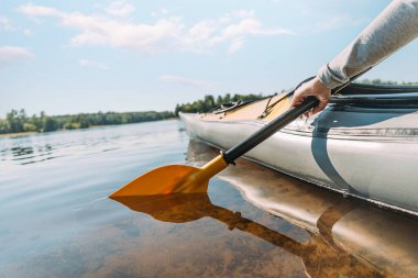 Genç bir kadın bir tekneyle nehirde yüzüyor. Kürekle eline odaklan. Yakın plan..