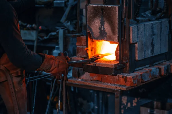 Blacksmith hardens a piece of metal in a special furnace. — Stockfoto
