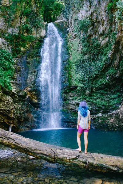 Jeune femme méconnaissable debout près de la cascade et le regardant. — Photo