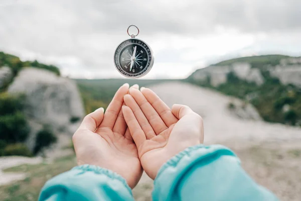 Kompas zweeft in levitatie over vrouwelijke handen in de achtergrond natuur. — Stockfoto