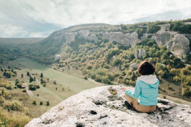 Traveler woman relaxing on peak of rock.