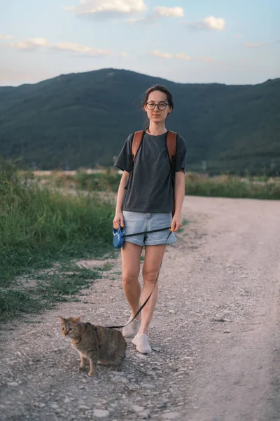 Woman walking with a cat on background of mountain ridge. — Zdjęcie stockowe