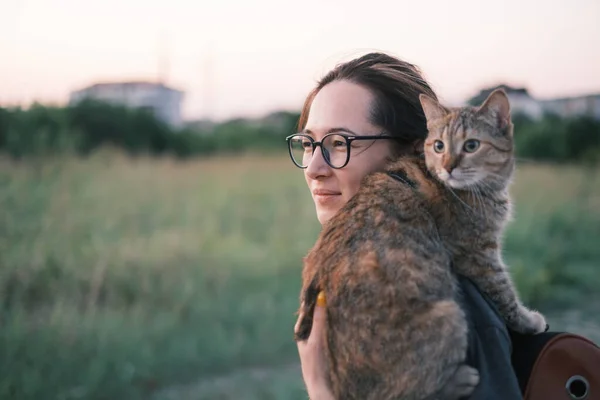 Улыбающаяся женщина идет с кошкой на открытом воздухе. — стоковое фото