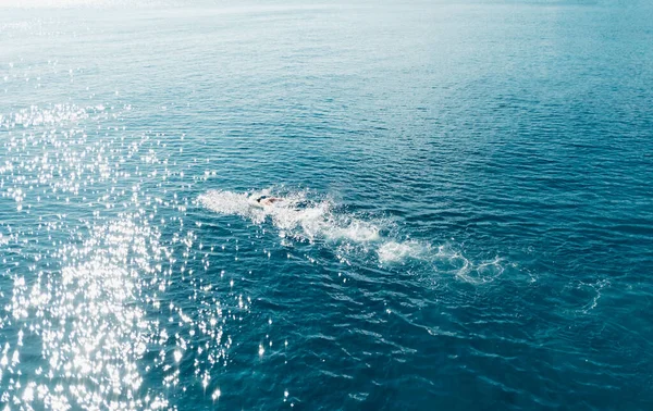 Человек плавает в синем море в солнечную погоду. — стоковое фото