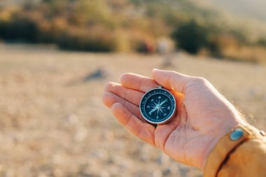 Compass lies in the palm of a tourist in the mountains during sunset.