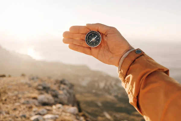 Tourist holds a compass against the backdrop of sunlight and beautiful landscape. — Stok fotoğraf