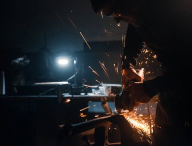 İşçi metali dairesel testereyle keser, kıvılcımlar yanlardan uçar..