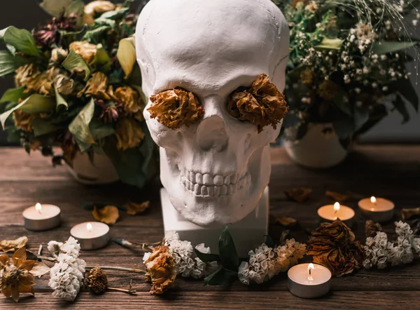 テーブルの上の枯れた花の花束と中央の頭蓋骨. — ストック写真