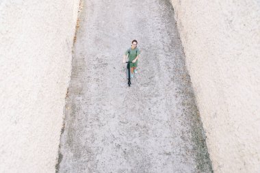 Genç bir kadın elektrikli scooterla yürüyor..