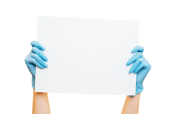 Las manos de mujer con guantes protectores sostienen un cartel blanco en blanco. —  Fotos de Stock