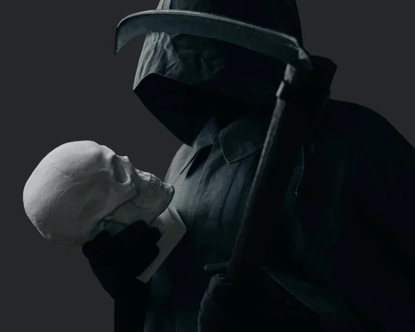 Grim Reaper with a scythe looking at skull. — Stock Photo, Image
