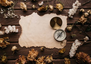 Kuru çiçekler arasında eski kağıt ve seyahat pusulası, kopyalama alanı.