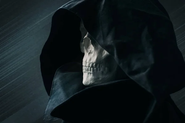 Close up view skull in black hood, on dark background. — Stock Photo, Image