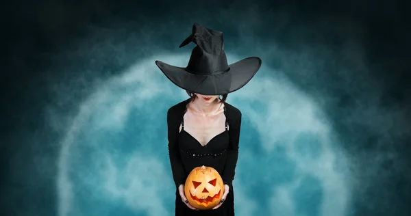 Heks houdt Halloween pompoen om middernacht — Stockfoto