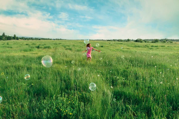 Kleines Mädchen mit Seifenblasen auf der Wiese — Stockfoto