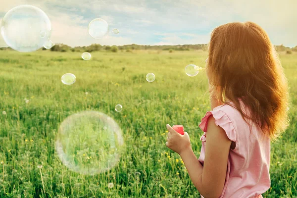 Девушка с мыльными пузырями на лугу — стоковое фото