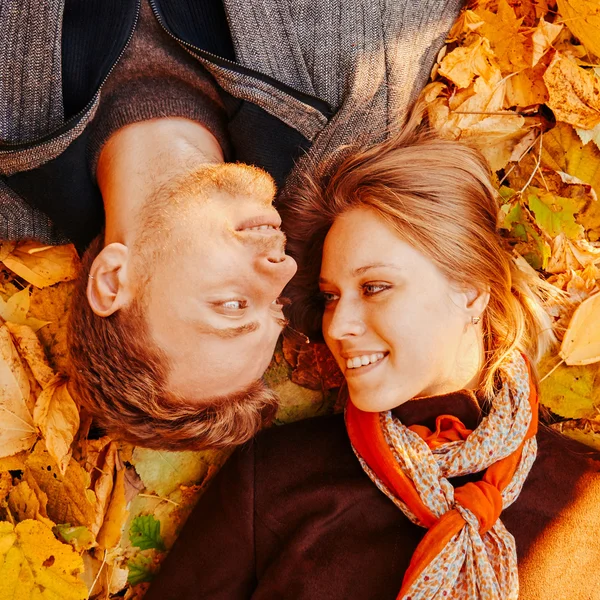 Sonriente pareja amorosa en hojas de otoño — Foto de Stock