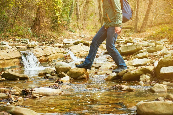 Man with backpack crossing river — Stock Photo, Image