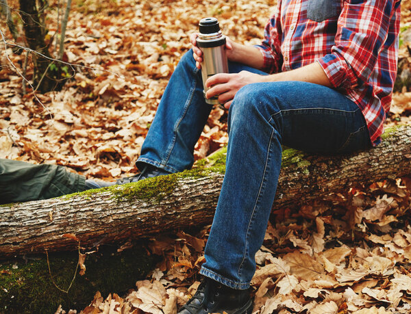 Man with cup of tea and thermos