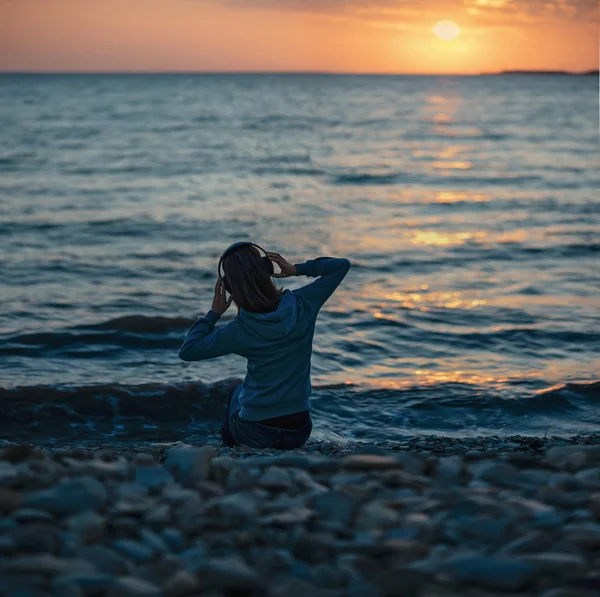 Девушка в наушниках на пляже — стоковое фото