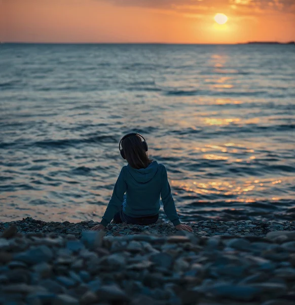 Flicka i hörlurar på stranden — Stockfoto