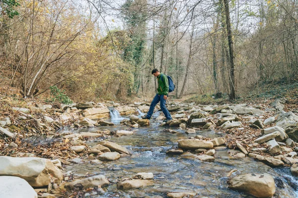 Hiker man korsar floden — Stockfoto