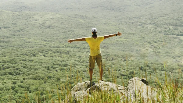 Hombre de pie con los brazos levantados en la roca — Foto de Stock