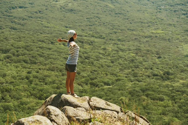 Женщина стоящая с поднятыми руками на скале — стоковое фото