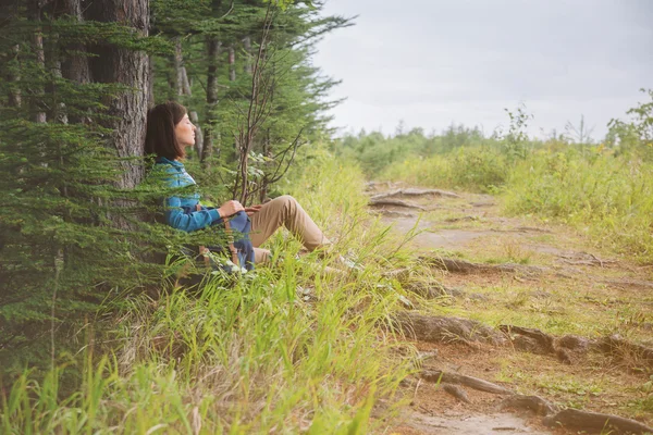 Женщина отдыхает у дерева в лесу — стоковое фото
