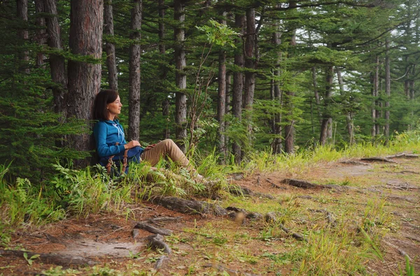Kobieta siedzi w pobliżu drzewa w lesie — Zdjęcie stockowe