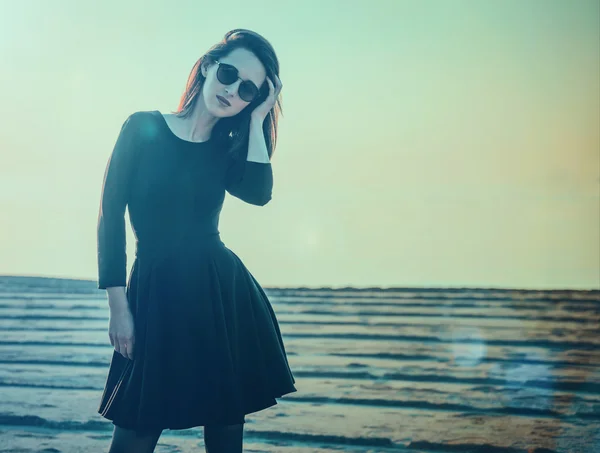 Vrouw in zwarte jurk staande op strand — Stockfoto