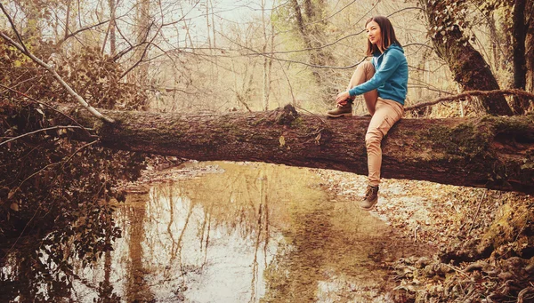 Dívka sedící na kmeni stromu — Stock fotografie