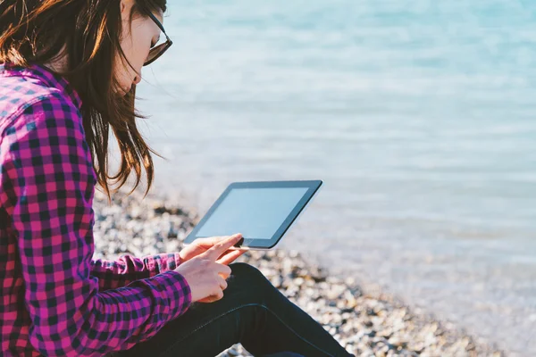 Kvinna sitter med digitala tablett på stranden — Stockfoto