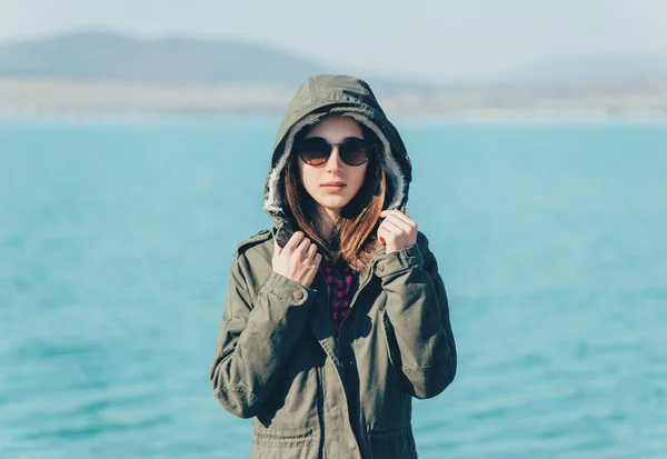 Menina em um casaco com capuz na costa — Fotografia de Stock