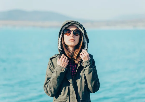 Девушка в куртке с капюшоном на фоне моря — стоковое фото
