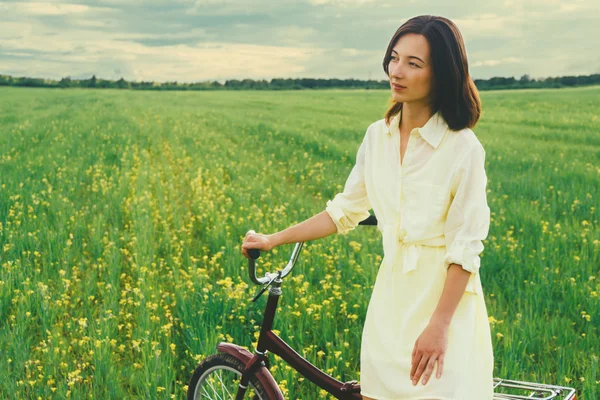 Woman resting with bicycle on meadow — Stock Photo, Image