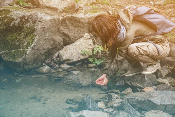 Mujer excursionista bebiendo agua de arroyo — Foto de Stock