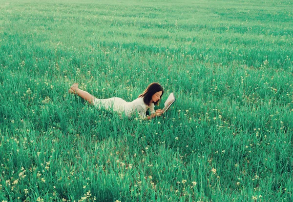 Mujer acostada en el prado y leyendo libro — Foto de Stock