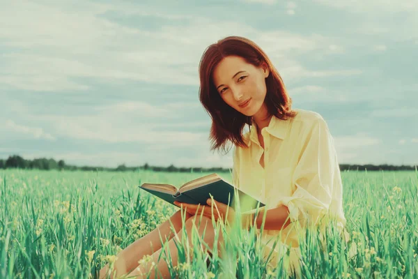 Nainen niityllä kirjan kanssa — kuvapankkivalokuva