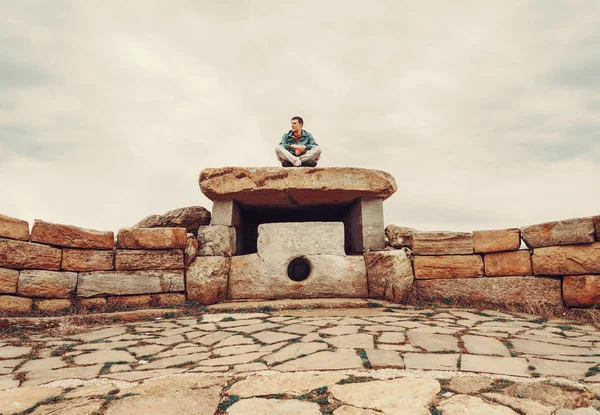 Üzerinde taş dolmen oturan seyahat adam