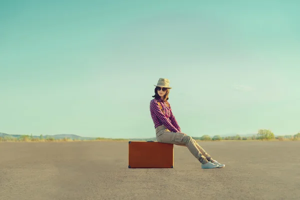 Viaggiatore ragazza seduta sulla valigia su strada — Foto Stock