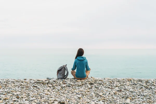 Chica viajera sentada en la costa — Foto de Stock