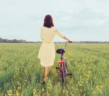 Bisiklet ile sahada yürüyen kadın
