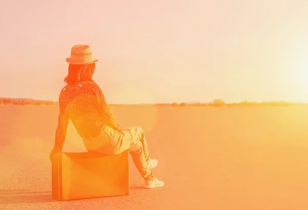 Woman sitting on suitcase on road. — Stock Photo, Image