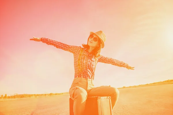 Hipster girl sits on vintage suitcase — Stock Photo, Image