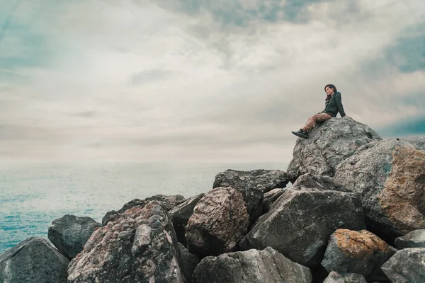 Mujer sentada en piedra cerca del mar — Foto de Stock