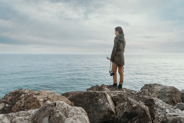 Chica viajera de pie en la costa de piedra — Foto de Stock